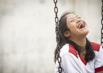 Niña ecuatoriana con discapacidad sentada en un columpio muy sonriente